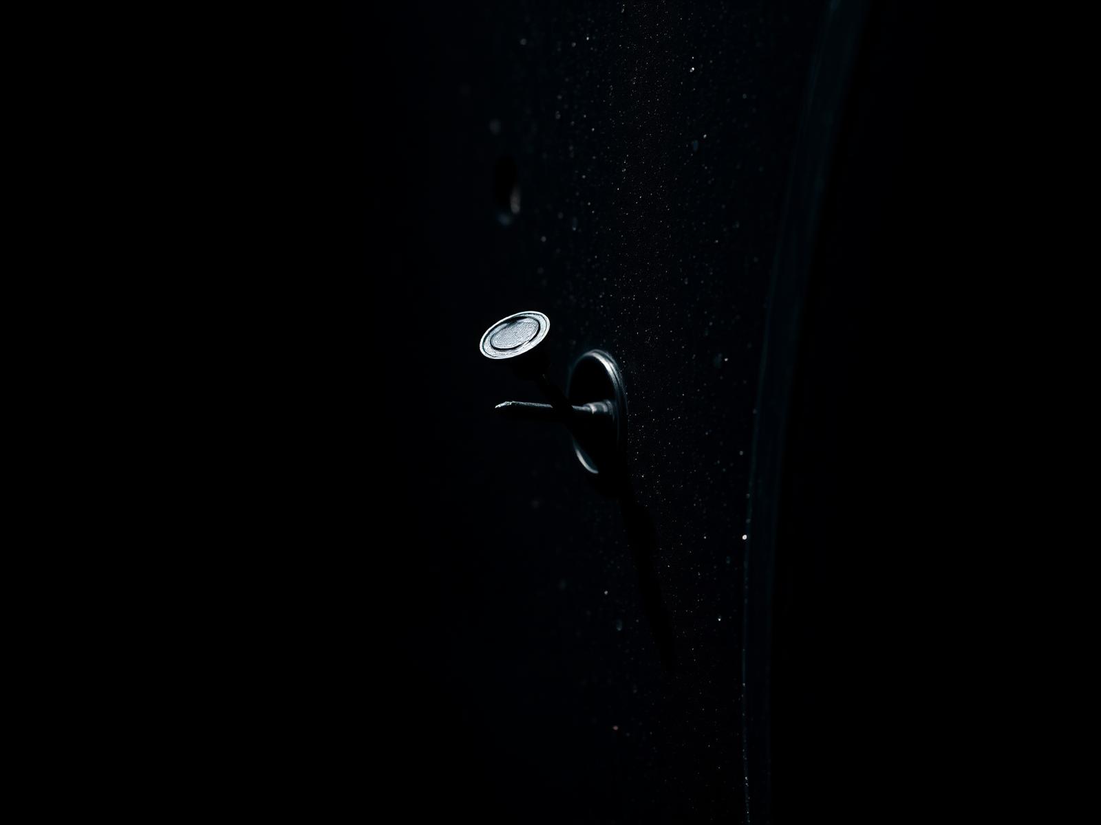 Close-up of a nail puncture in a black car tire — common cause of slow leaks repairable with a patch-plug combination